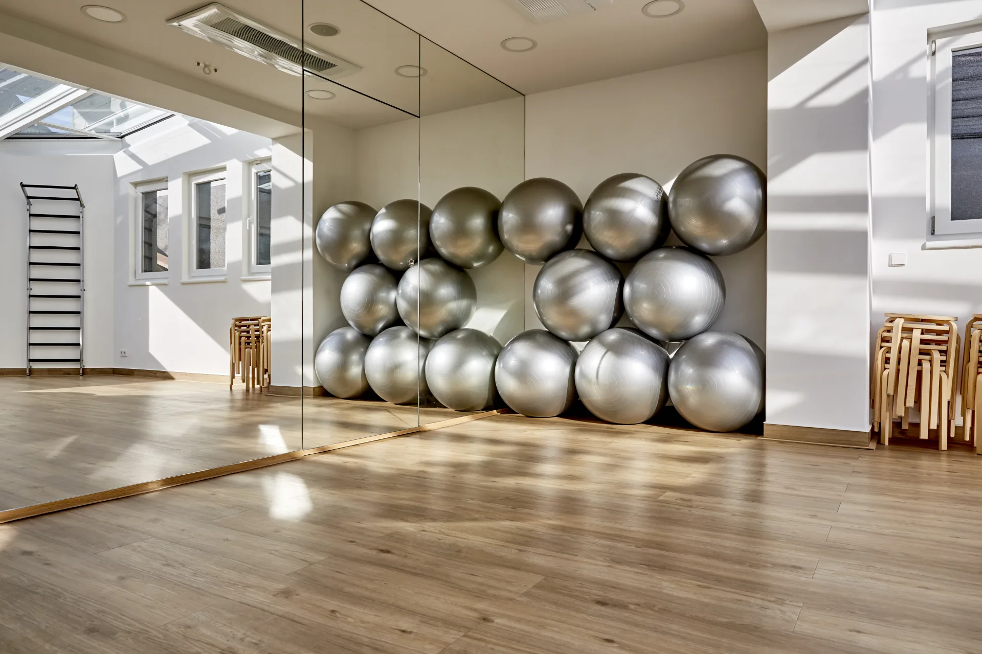 Moderner, geräumiger Bewegungsraum bei PHYSIOMED SÜD Berlin mit Spiegelwand, Sprossenwand und Gymnastikbällen für aktive Therapien – ideal für Physiotherapeuten, die aktiv arbeiten möchten.