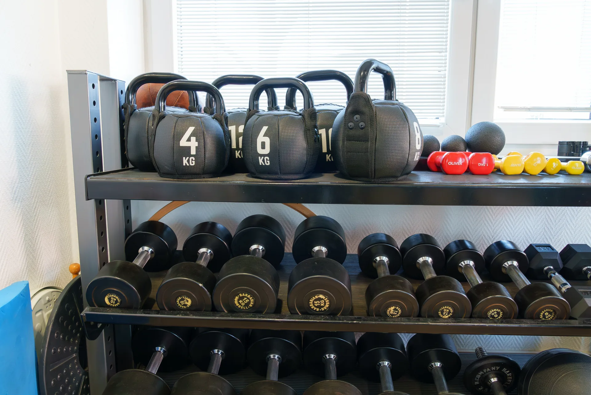 Professionelles Trainingszubehör mit Kettlebells und Kurzhanteln im Geräteraum der Praxis PHYSIOMED SÜD Berlin für die aktive Krankengymnastik.