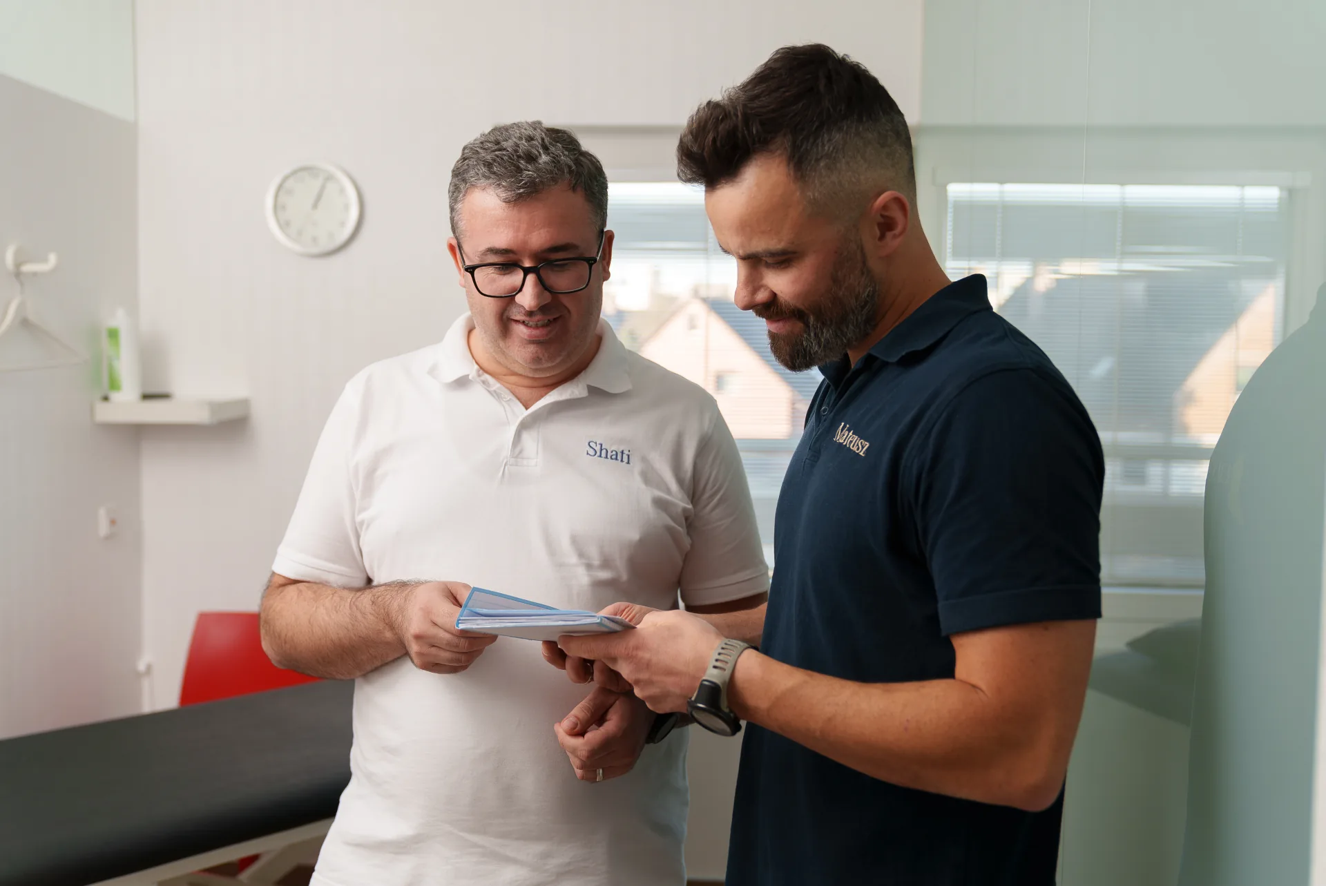 Zwei Therapeuten im kollegialen Austausch über eine Behandlungsakte in der Praxis PHYSIOMED SÜD Berlin – Fokus auf Teamarbeit und professionelle Patientenversorgung.